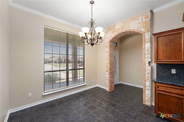 unfurnished dining area featuring dark tile patterned flooring, an inviting chandelier, and ornamental molding