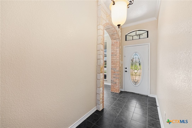 entrance foyer with dark tile patterned flooring and crown molding