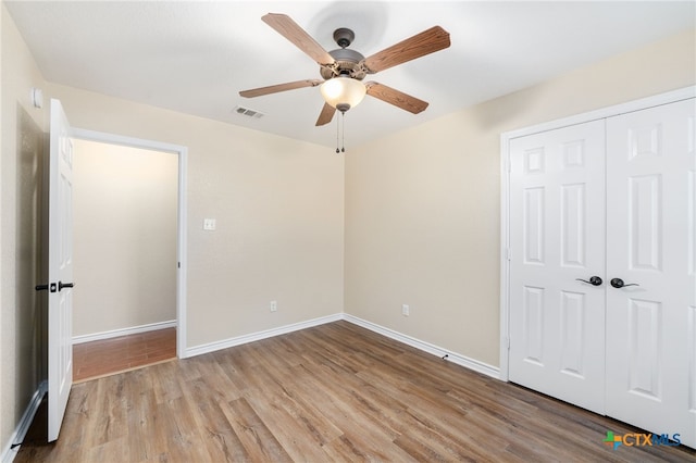 unfurnished bedroom featuring light wood-type flooring, ceiling fan, and a closet