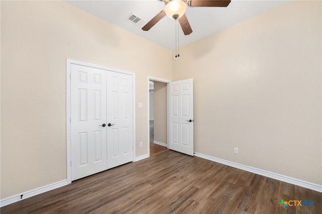 unfurnished bedroom with dark wood-type flooring, ceiling fan, a high ceiling, and a closet