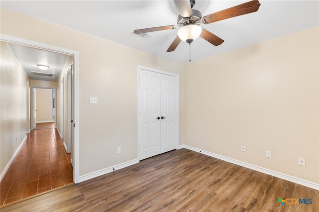 unfurnished bedroom featuring wood-type flooring, ceiling fan, and a closet