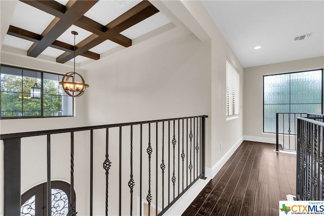 hall with a healthy amount of sunlight, dark hardwood / wood-style floors, coffered ceiling, and an inviting chandelier