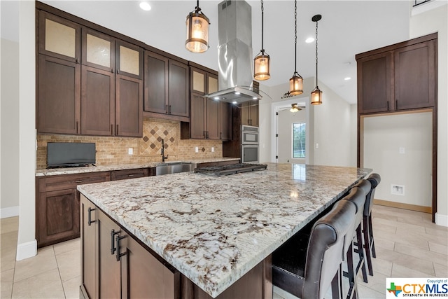 kitchen with decorative light fixtures, island exhaust hood, a center island, and light stone countertops