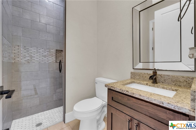 bathroom with tiled shower, tile patterned flooring, vanity, and toilet