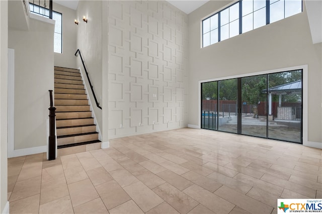 unfurnished living room featuring light tile patterned floors and a towering ceiling