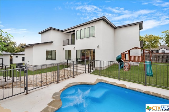 back of house featuring a balcony, a fenced in pool, a yard, and cooling unit