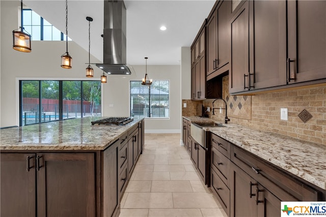 kitchen featuring pendant lighting, a healthy amount of sunlight, island range hood, and light stone countertops