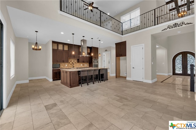 kitchen featuring a kitchen island with sink, plenty of natural light, island range hood, and backsplash