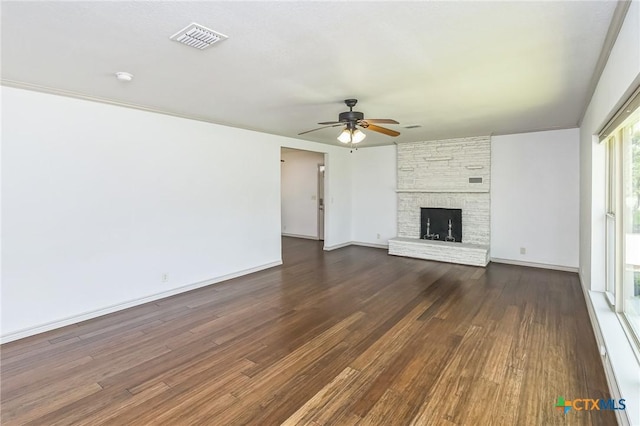 102 Norcrest Dr, San Marcos, TX 78666 - unfurnished living room with a ceiling fan, dark wood-style flooring, a stone fireplace, and baseboards