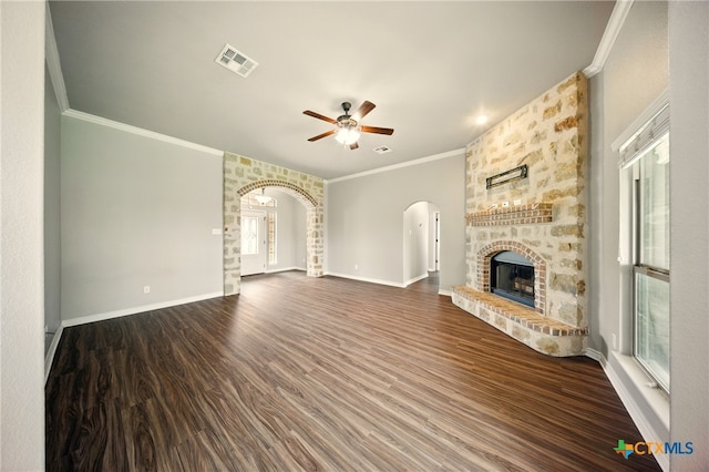 412 Coventry Dr, Temple, TX 76502 - unfurnished living room featuring arched walkways, ceiling fan, ornamental molding, dark wood finished floors, and a stone fireplace