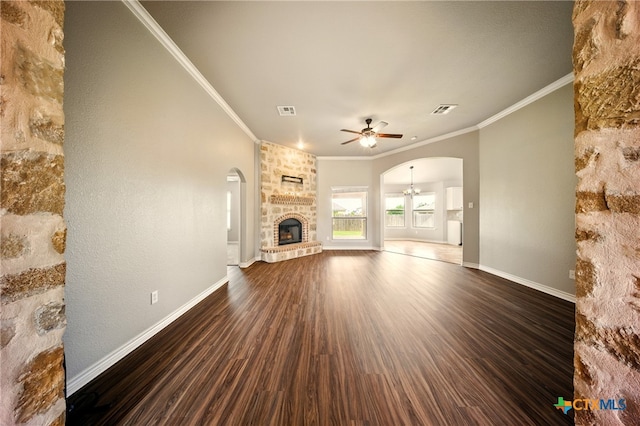 412 Coventry Dr, Temple, TX 76502 - unfurnished living room featuring ceiling fan, arched walkways, a fireplace, dark wood-style flooring, and crown molding