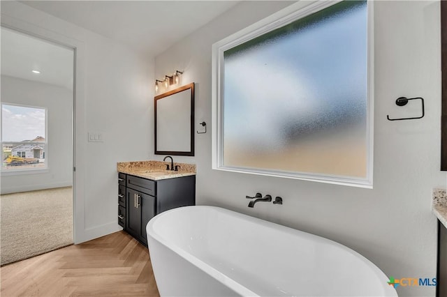 bathroom featuring vanity, parquet flooring, and a bathtub