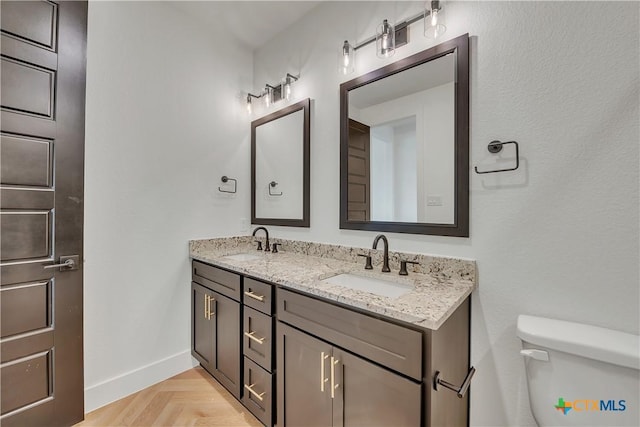 bathroom featuring parquet floors, vanity, and toilet