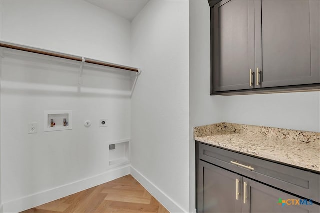 clothes washing area featuring cabinets, hookup for a gas dryer, hookup for a washing machine, light parquet flooring, and hookup for an electric dryer