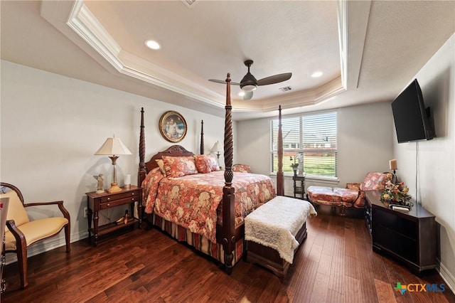 bedroom featuring dark wood-style flooring, a raised ceiling, visible vents, ornamental molding, and baseboards