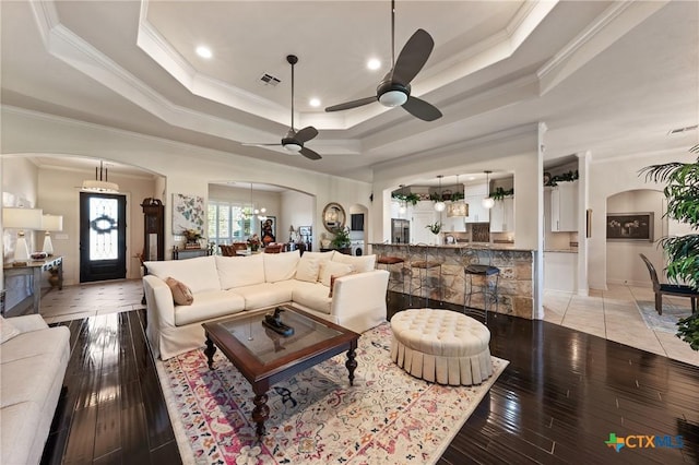 living area featuring arched walkways, a raised ceiling, and visible vents