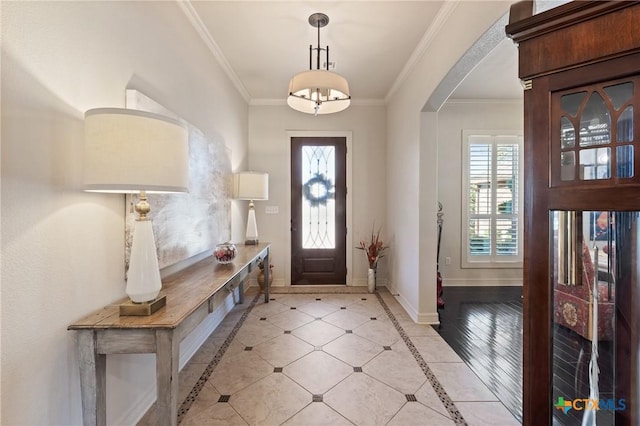 foyer with crown molding, baseboards, arched walkways, and a wealth of natural light