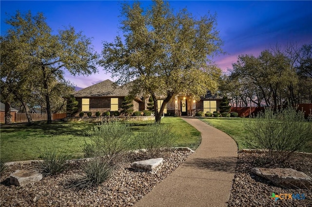 view of front facade featuring stone siding, a front lawn, and fence