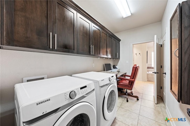 clothes washing area featuring cabinet space, washing machine and dryer, light tile patterned floors, and baseboards