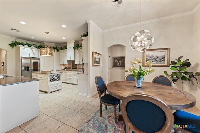 dining room featuring light tile patterned floors, visible vents, arched walkways, and ornamental molding