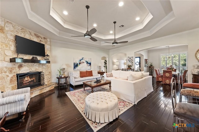 living room featuring a fireplace, visible vents, a raised ceiling, and dark wood-style flooring