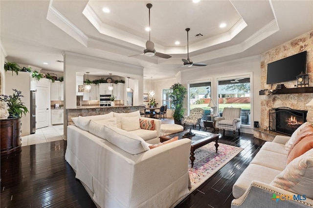 living area featuring light wood-type flooring, visible vents, a fireplace, and a tray ceiling