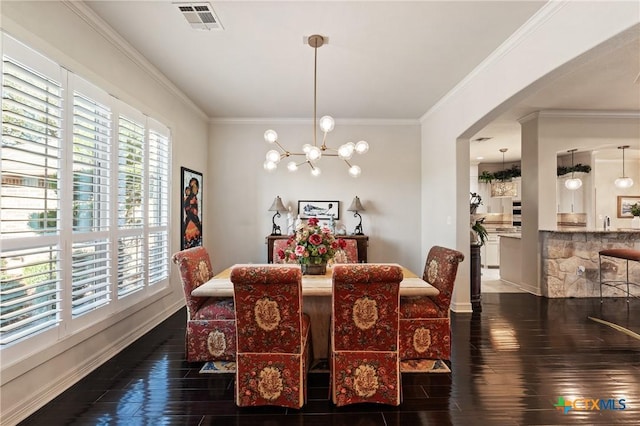 dining room with ornamental molding, a chandelier, visible vents, and wood finished floors