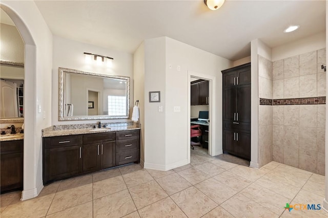 full bathroom with tile patterned flooring, vanity, baseboards, and a walk in shower