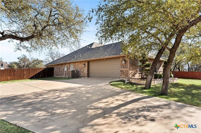 view of front facade with brick siding, concrete driveway, central AC unit, fence, and a garage