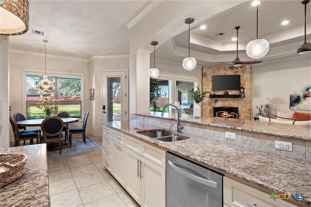 kitchen featuring open floor plan, stainless steel dishwasher, a sink, and crown molding