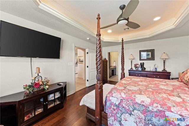 bedroom featuring ornamental molding, a tray ceiling, dark wood finished floors, and visible vents