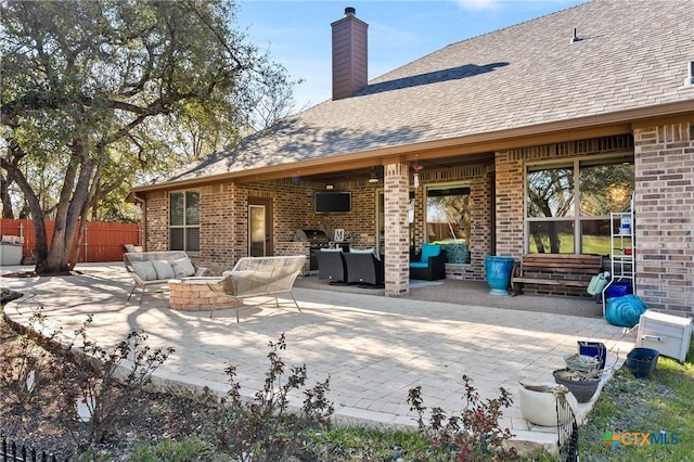 back of property with brick siding, a patio, a chimney, an outdoor hangout area, and fence