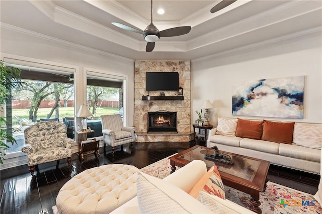 living room with wood-type flooring, ornamental molding, a raised ceiling, and a ceiling fan