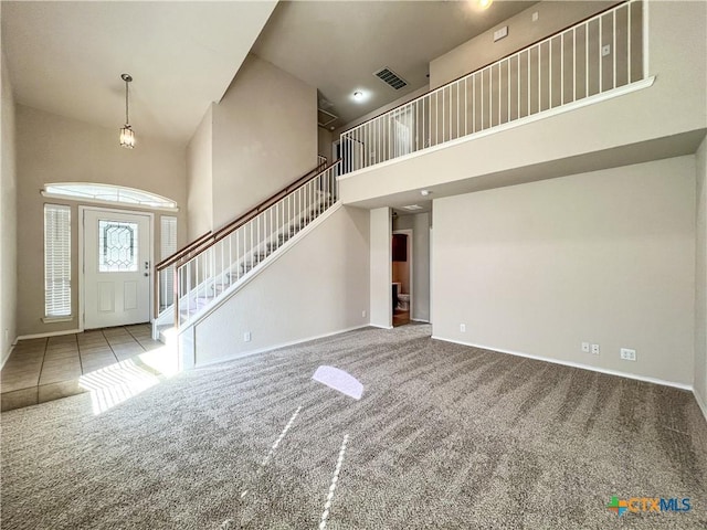 foyer with carpet floors and a towering ceiling