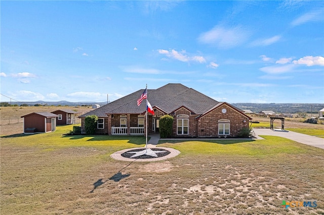 single story home with a porch, a storage shed, and a front yard