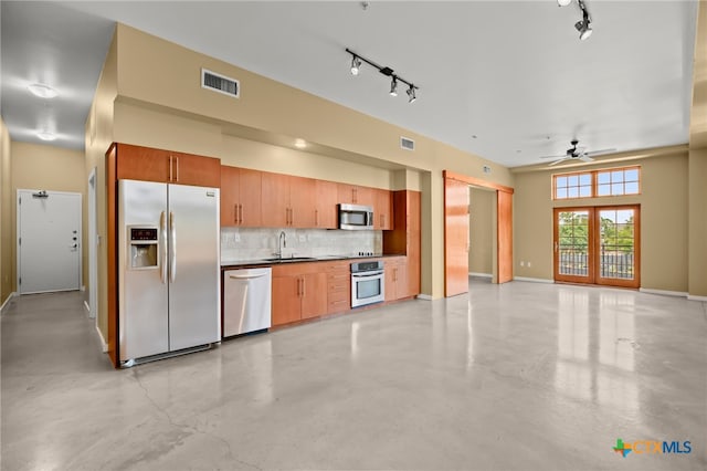 kitchen with decorative backsplash, sink, track lighting, and stainless steel appliances