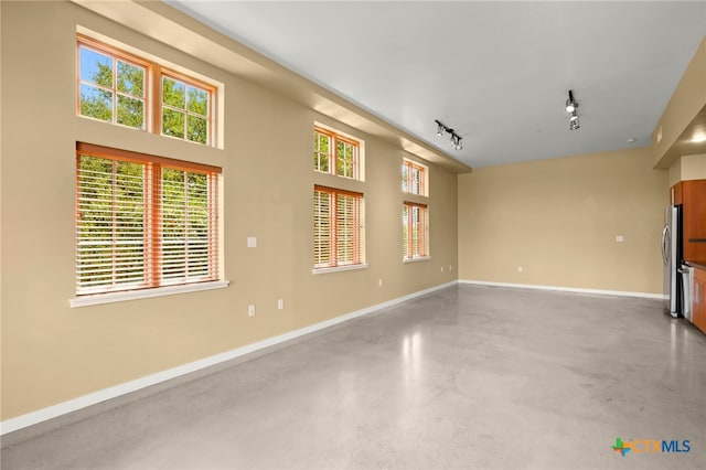 unfurnished living room featuring concrete flooring and track lighting