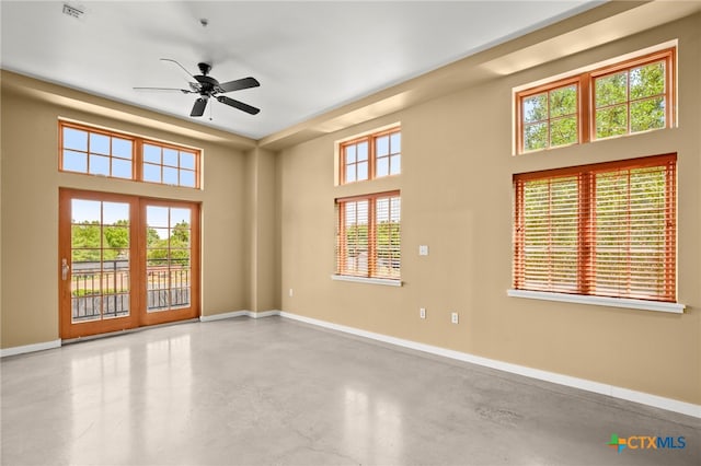 spare room featuring plenty of natural light, ceiling fan, and concrete floors