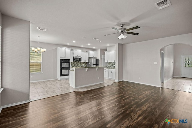 5712 Stonehaven Dr, Temple, TX 76502 - unfurnished living room featuring light wood-type flooring, arched walkways, a ceiling fan, baseboards, and recessed lighting