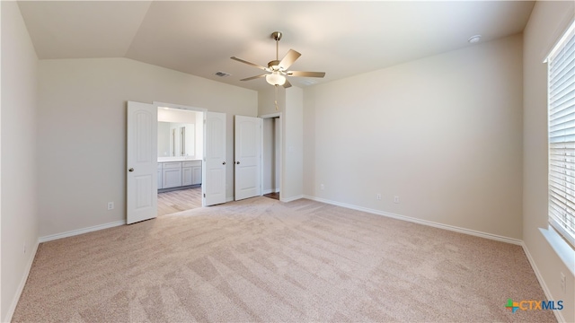 unfurnished bedroom featuring ceiling fan, vaulted ceiling, light colored carpet, and multiple windows