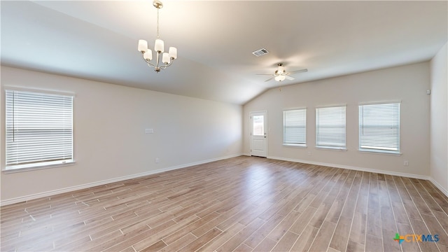 empty room featuring ceiling fan with notable chandelier, light hardwood / wood-style flooring, and vaulted ceiling