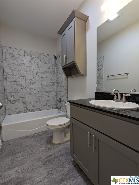 full bathroom featuring vanity, tiled shower / bath, and toilet