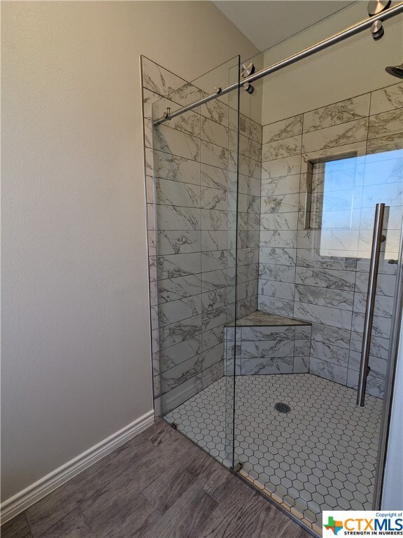 bathroom featuring wood-type flooring and a tile shower