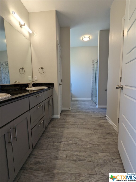 bathroom featuring walk in shower, vanity, and hardwood / wood-style flooring