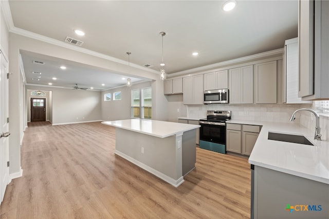 kitchen featuring gray cabinetry, stainless steel appliances, light wood-type flooring, decorative light fixtures, and a center island