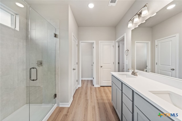 bathroom with hardwood / wood-style floors, a shower with shower door, and vanity