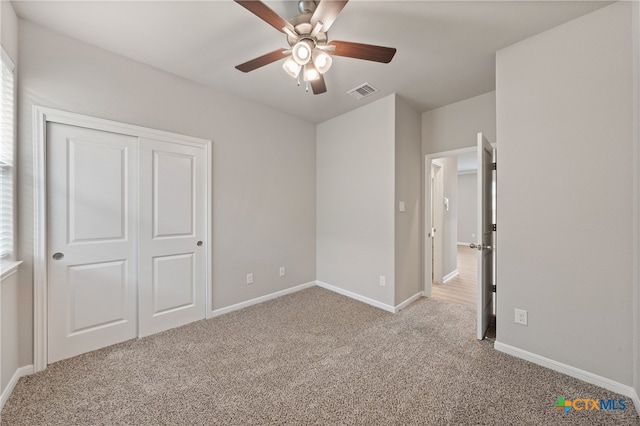 unfurnished bedroom featuring ceiling fan, light carpet, and a closet