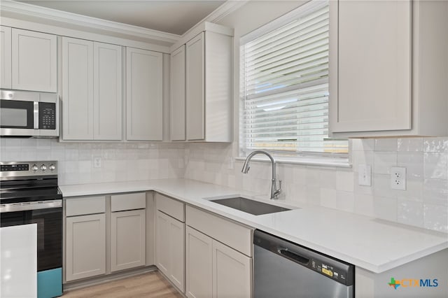 kitchen featuring decorative backsplash, sink, ornamental molding, and stainless steel appliances