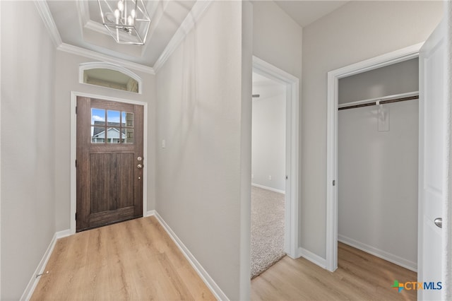 foyer entrance featuring light wood-type flooring, a chandelier, and crown molding