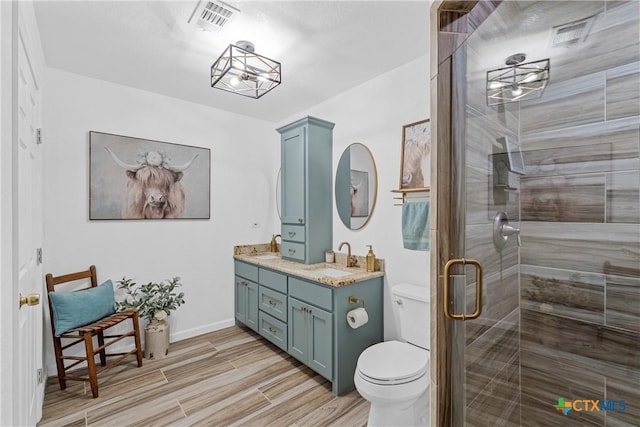 bathroom featuring wood finished floors, visible vents, toilet, vanity, and a stall shower